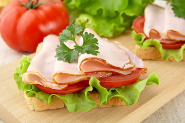 Toasts with tomato in the background on cutting board