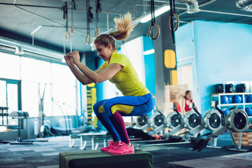 Fitness woman jumping on box training at the gym, girl in leggins and a t-shirt