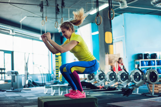 Fitness woman jumping on box training at the gym, girl in leggins and a t-shirt - Powered by Adobe