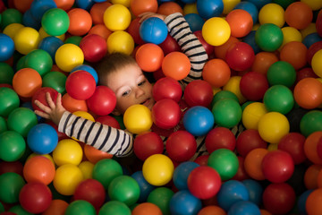 boy having fun in hundreds of colorful plastic balls