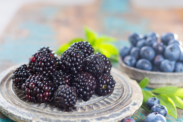 Fresh summer wild blueberries and brambleberry, blackberry in stone bowls