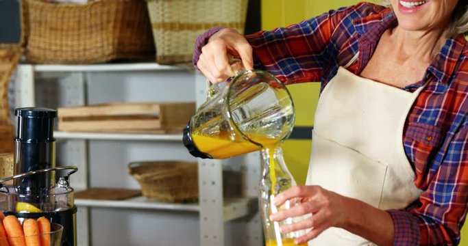 Woman pouring orange juice into a bottle