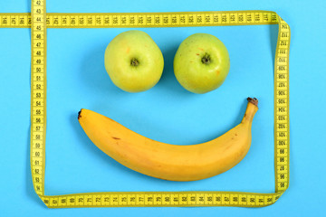 Smile made of banana and green apples framed with ruler
