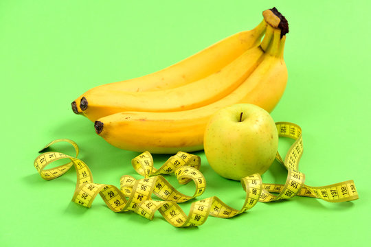 Apple in green color, bananas and yellow tape for measuring
