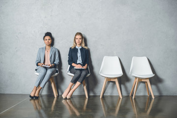 young multicultural businesswomen sitting on chairs and waiting for job interview