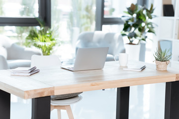 empty modern workplace with laptop, coffee cup and notebooks in office