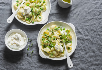 Pasta with green peas, asparagus and fresh ricotta. On a gray background, top view. Healthy...