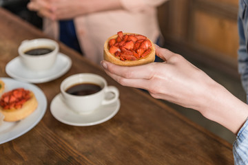 cropped view of woman holding strawberry tart during lunch