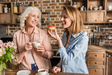 Portrait of two women, senior and young eating strawberry tart during their lunch