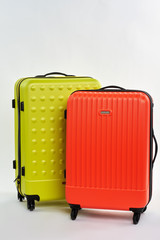 Bright summer suitcases for sale. Plastic wheeled bags for resort, white background.