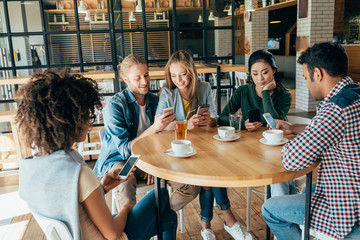 Group of young multiethnic friends spending good time together in cafe