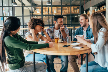 Group of young multiethnic friends spending good time together in cafe