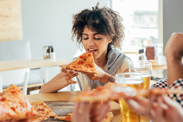 young african american woman eating pizza in cafe