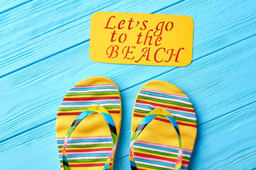 Cropped image of striped slippers. Message above pair of sandals. Concept of beach rest.