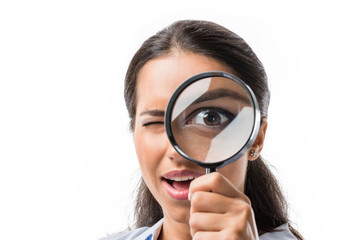 portrait of businesswoman looking at camera thorough magnifying glass isolated on white