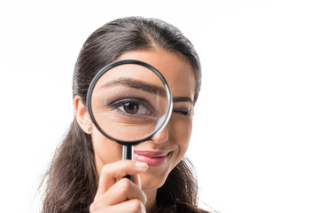 portrait of businesswoman looking at camera thorough magnifying glass isolated on white