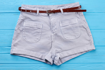Modern cotton shorts with belt. Comfortable female summer short pants, blue background.