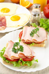 Sandwiches with eggs on plate for breakfast on linen tablecloth