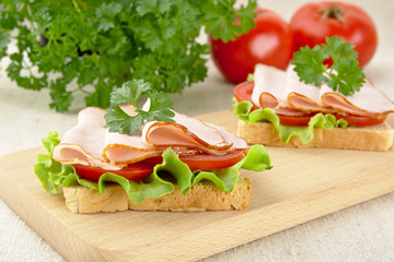 Toasts with tomato in the background on cutting board