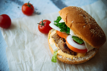 Two hamburgers with beef burger cutlet, fried onion, spinach, ketchup sauce and blue cheese in traditional buns, served on wood chopping board over bright turquoise background. Copy space