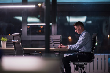 man working on laptop in dark office