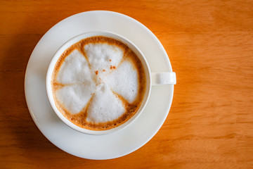 Hot cappuccino cup on wood table.