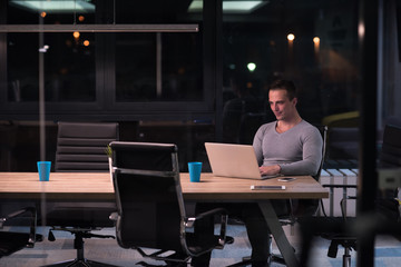 man working on laptop in dark office