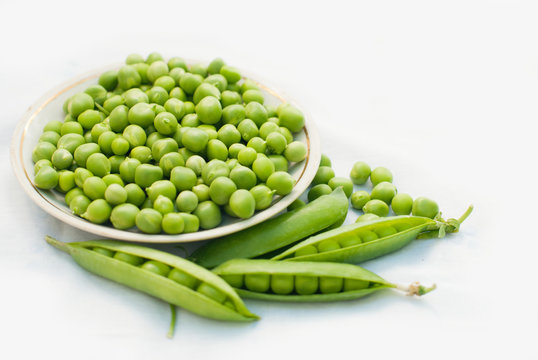 Green pea and pods in a bowl of top view on white background with copy space - healthy food - Flat lay