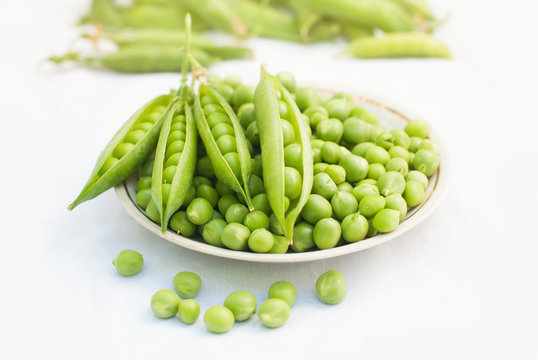 Green pea and pods in a bowl of top view on white background with copy space - healthy food - Flat lay