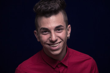 Obraz premium ordinary portrait, one teenager boy, red shirt, Caucasian, dark background, looking to camera, smiling