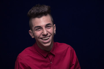 one teenager boy, red shirt, Caucasian, dark background, looking to camera, laughing