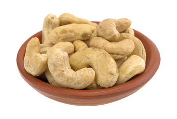Raw cashews in a small red clay bowl isolated on a white background.