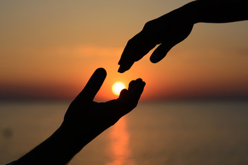 A man holds the sun in his hands and gives it to his beloved girl. Love and romance.