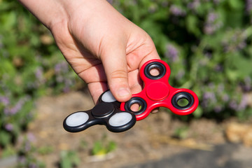 Boy playing with two fidget spinner stress relieving toys outdoor