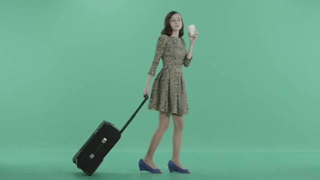 a young girl with luggage walks drinking coffee