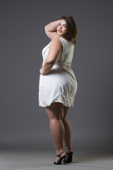 Happy plus size fashion model in casual clothes, fat woman on gray background, overweight female...