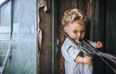 Old doll pressed to the wall with garden forks. Aggression, cruelty, fear. Chernobyl catastrophe.