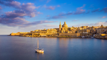 Valletta, Malta - St.Paul's Cathedral in golden hour at Malta's capital city Valletta with sailboat and beautiful colorful sky and clouds - obrazy, fototapety, plakaty
