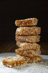 Traditional Vietnamese sweetness. Nougat with sesame seeds and peanuts on paper on a dark background. Close-up, copy space.