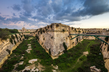Fototapeta na wymiar Manoel Island, Malta - Abandoned limestone fortress at the center of Manoel Island with Saint Paul's Cathedral and Valletta at the background