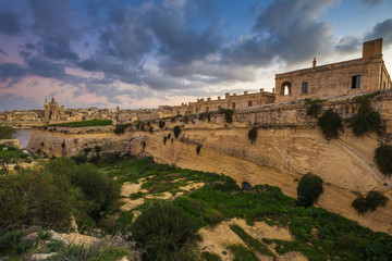 Fototapeta na wymiar Manoel Island, Malta - Abandoned limestone fortress at the center of Manoel Island with Saint Paul's Cathedral and Valletta at the background