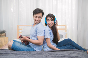 Couple relaxing with happiness and joyful and play ukulele song in bedroom