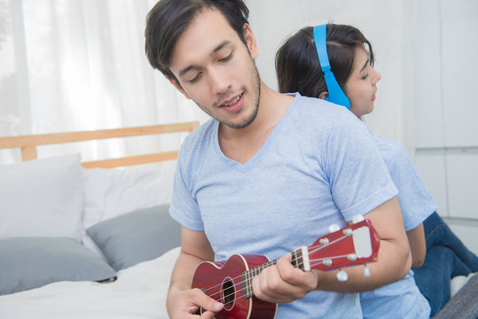 Couple relaxing with happiness and joyful and play ukulele song in bedroom