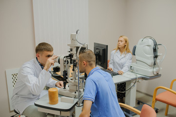 Obraz premium Young beautiful doctor/eye specialist/optometrist in an ophthalmologic clinic examines a patient