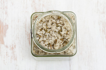salt with herbs in jar on wooden background