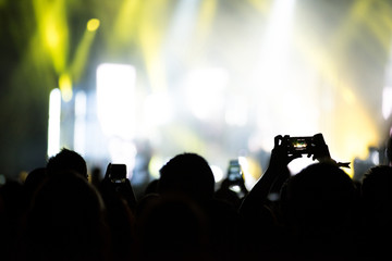 Raised arms holding smart phones to recording a live concert