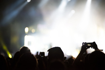 Raised arms holding smart phones to recording a live concert