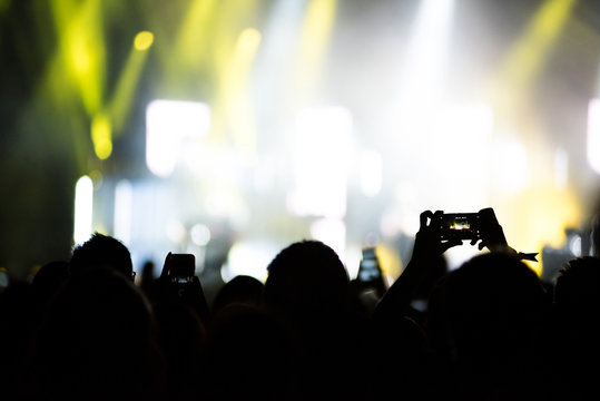 Raised arms holding smart phones to recording a live concert
