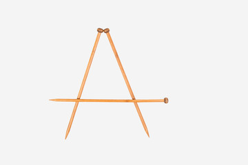 Alphabet letter A is arranged from knitting needles. Top view. Isolated on white background