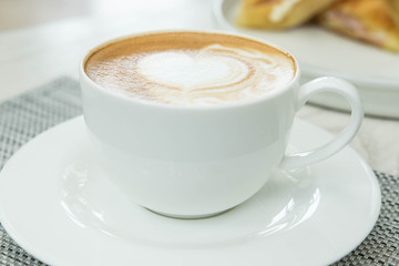 Heart shape of latte art coffee in white cup  on desk